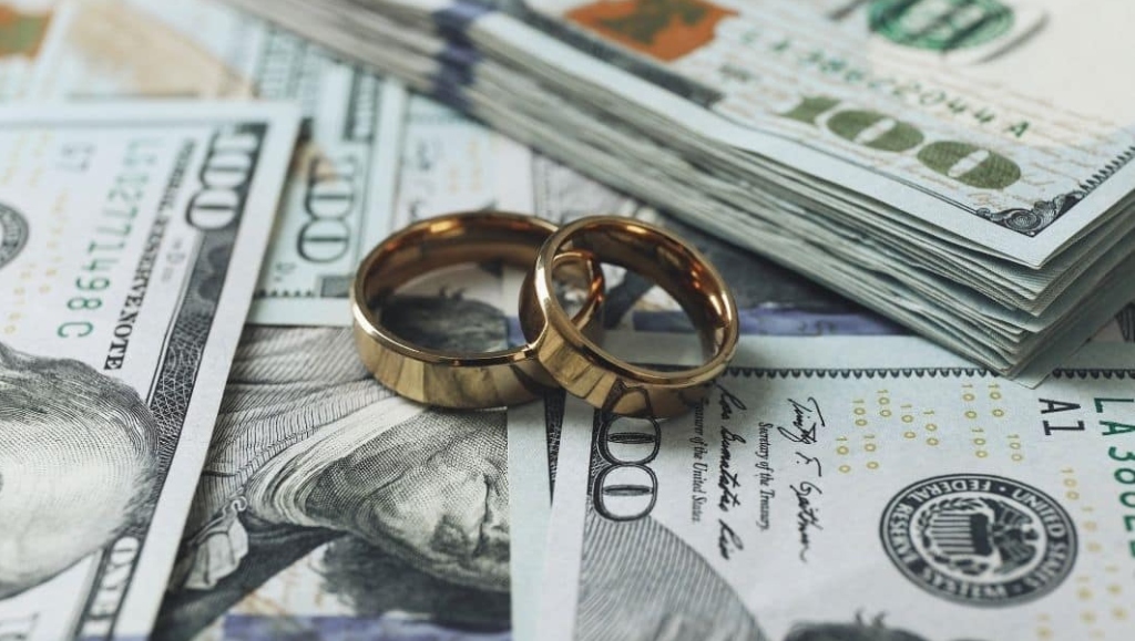 Image of wedding bands lying on top of hundred dollar bills.